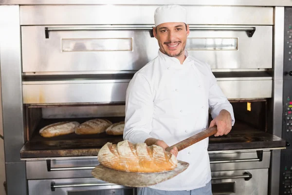 Felice panettiere tirando fuori pane fresco — Foto Stock