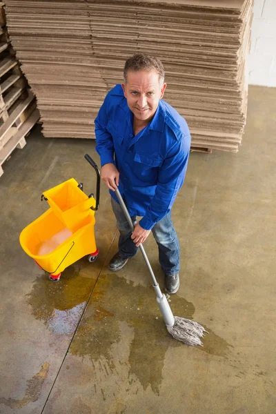 Smiling man moping warehouse floor — Stock Photo, Image