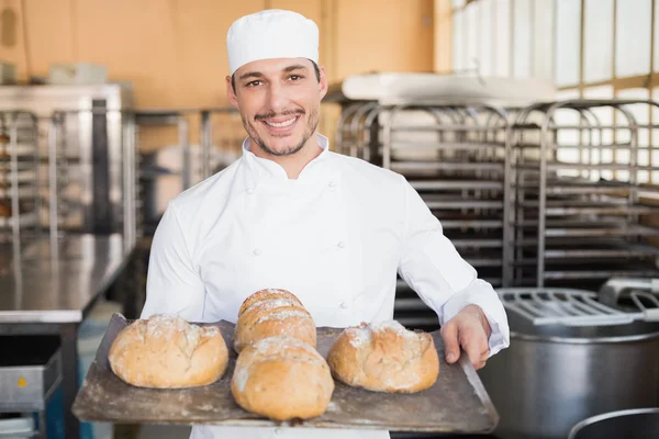 Happy baker showing tray of fresh bread — Stock Photo, Image