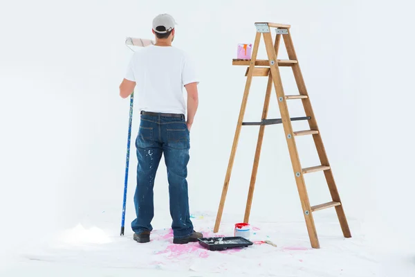 Hombre con rodillo de pintura de pie por escalera — Foto de Stock