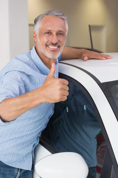 Мужчина обнимает машину, показывая большие пальцы. — стоковое фото