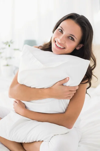 Sonriente morena sentada en la cama — Foto de Stock