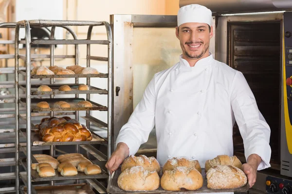 Happy baker showing tray of fresh bread — Stock Photo, Image