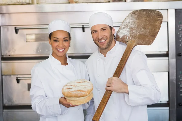 Пекари улыбаются в камеру с буханкой — стоковое фото