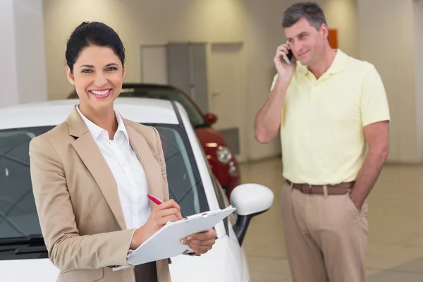 Mujer de negocios sonriente escribiendo en portapapeles — Foto de Stock