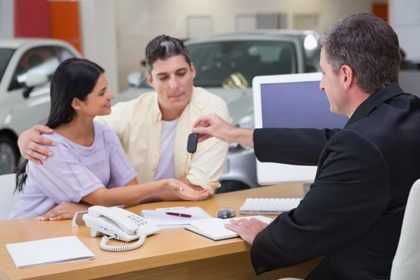 Salesman giving car keys to a couple — Stock Photo, Image
