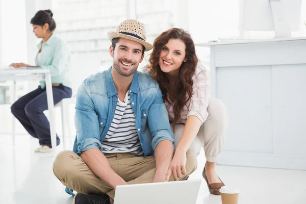 Collega's zittend op de vloer met behulp van laptop — Stockfoto