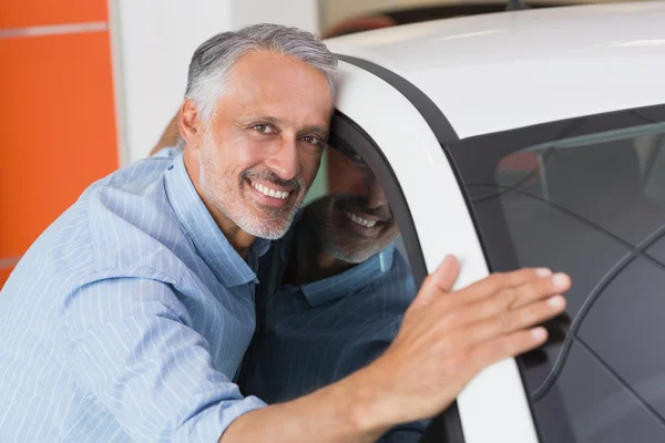 Smiling man hugging car — Stock Photo, Image