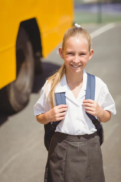 Cute pupil smiling at camera by the school bus — Stock Photo, Image