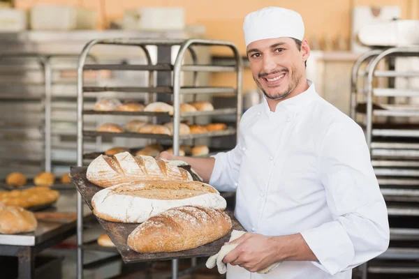 Gülümseyen baker ekmek tepsi tutarak — Stok fotoğraf