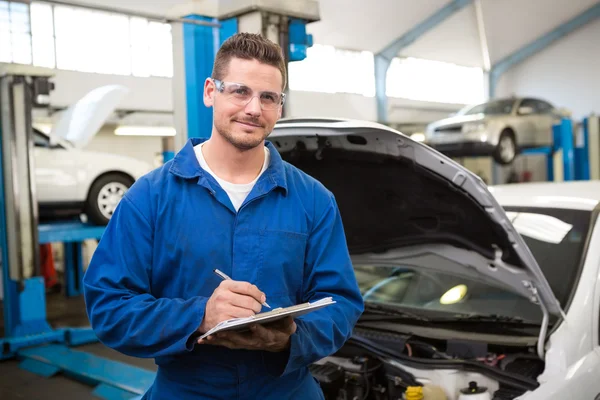 Lächelnder Mechaniker schreibt auf Klemmbrett — Stockfoto