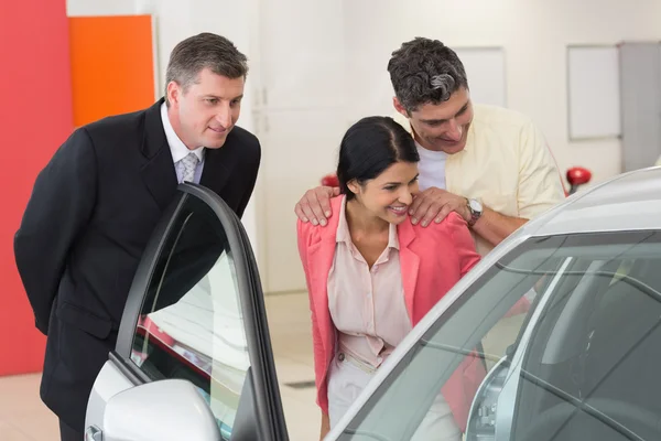 Carro revendedor mostrando interior do carro para casal — Fotografia de Stock