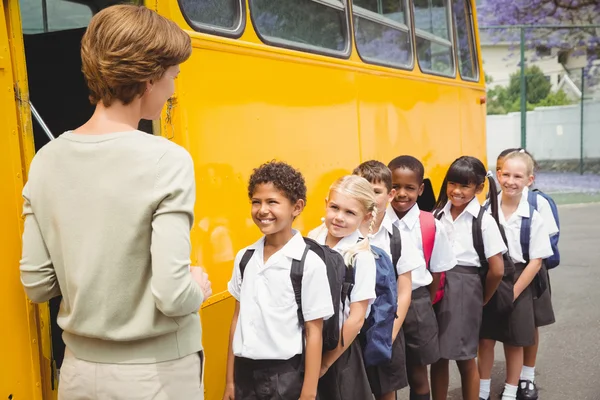 Écoliers mignons attendant de monter dans le bus scolaire — Photo