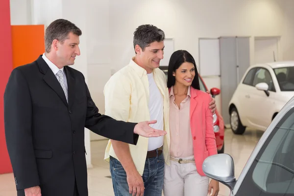Smiling businessman presenting a car — Stock Photo, Image