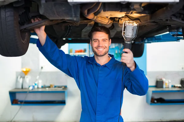Mechaniker schaut mit Taschenlampe unter Auto — Stockfoto