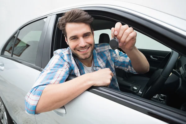 Junger Mann lächelt und hält Schlüssel in der Hand — Stockfoto