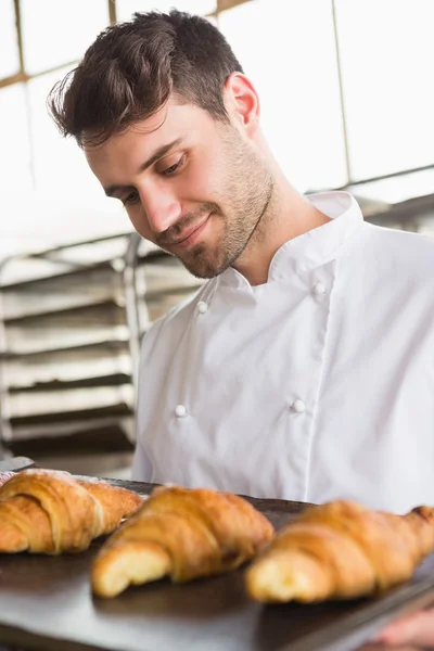 Baker showing tray of fresh croissant — Stock Photo, Image