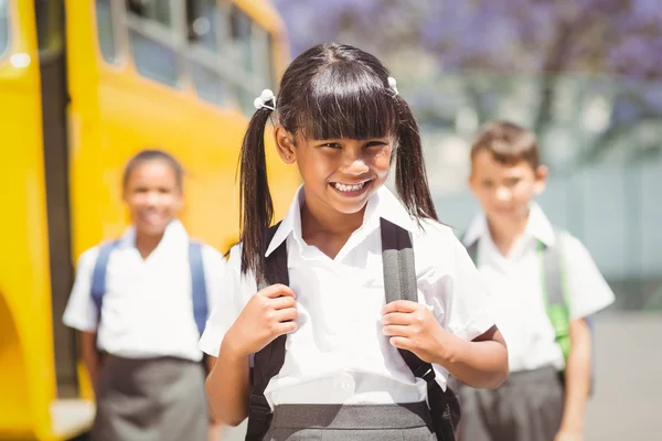 Aluno bonito sorrindo para a câmera pelo ônibus escolar — Fotografia de Stock