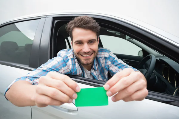 Young man smiling and holding card — Stock Photo, Image