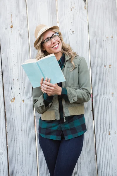 Loira sorridente em chapéu segurando livro — Fotografia de Stock