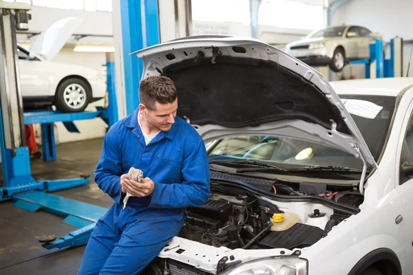 Mecânico sorridente olhando para o carro — Fotografia de Stock