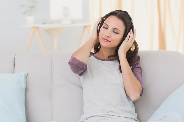 Brunette luisteren naar muziek op Bank — Stockfoto