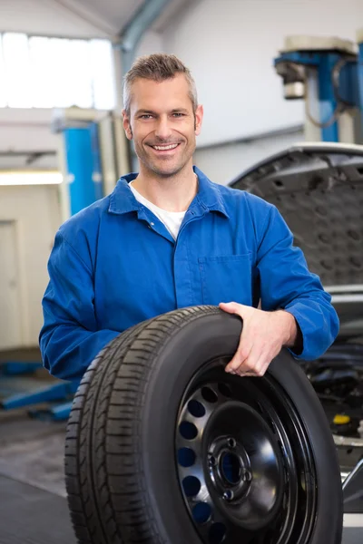 Mechaniker hält ein Reifenrad — Stockfoto