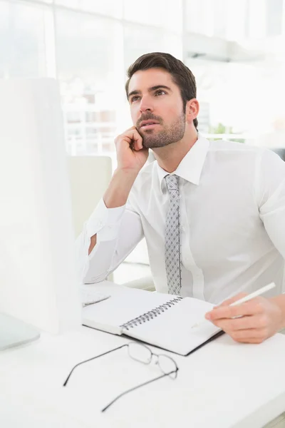 Pensativo hombre de negocios escribiendo en bloc de notas — Foto de Stock