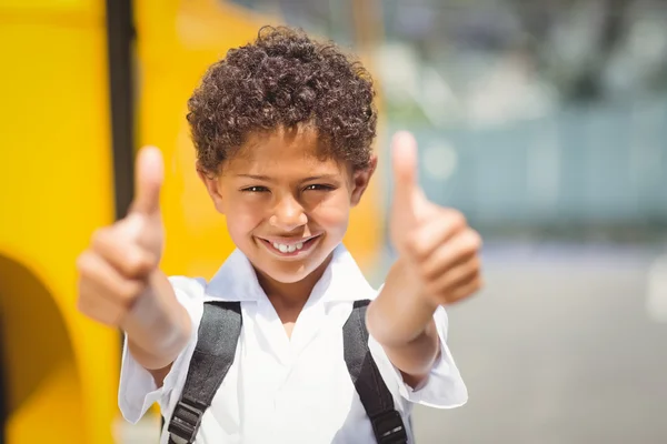 Симпатичный ученик улыбается в камеру возле школьного автобуса — стоковое фото