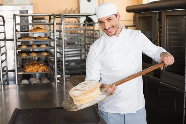 Happy baker taking out fresh loaf — Stock Photo, Image