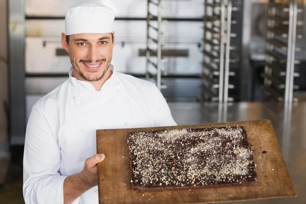 Baker showing freshly baked brownie — Stock Photo, Image