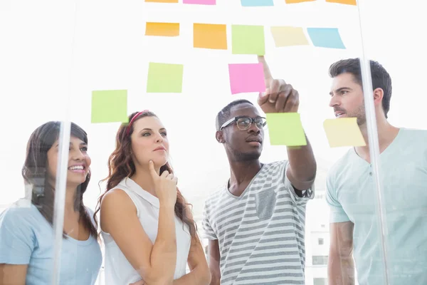 Kollegen zeigen auf klebrige Notizen und interagieren — Stockfoto