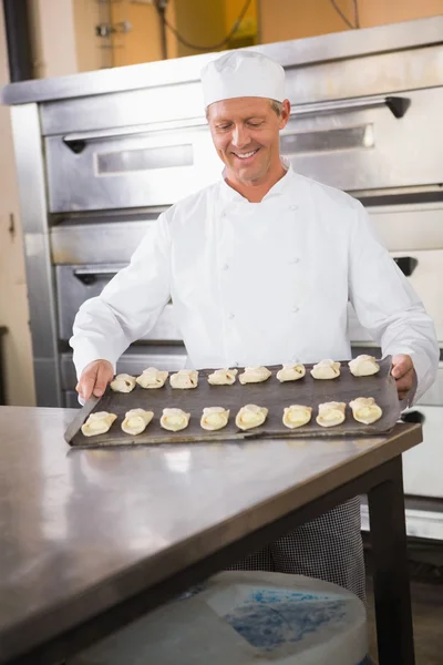Baker holding tray of raw dough — Stock Photo, Image