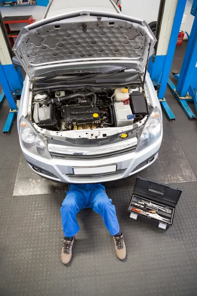 Mechaniker liegt und arbeitet unter Auto — Stockfoto