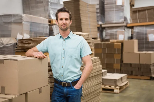 Magazijnmedewerker leunend tegen vakken — Stockfoto