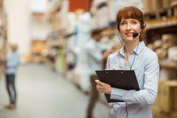 Manager bär ett headset samtidigt som du håller Urklipp — Stockfoto