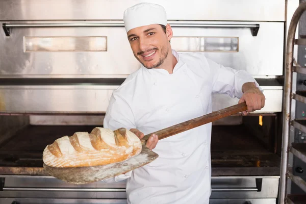 Happy baker taking out fresh loaf — Stock Photo, Image