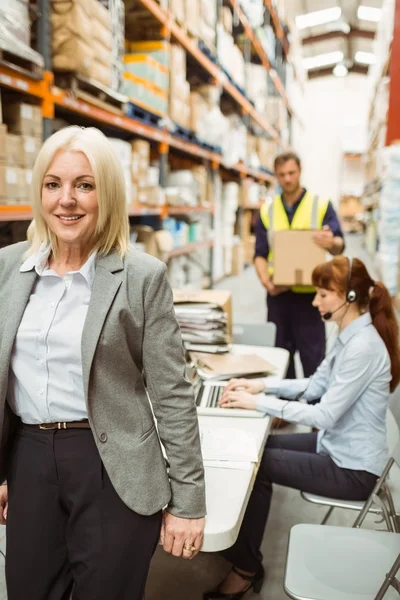 Smiling warehouse manager leaning on desk — Stock Photo, Image