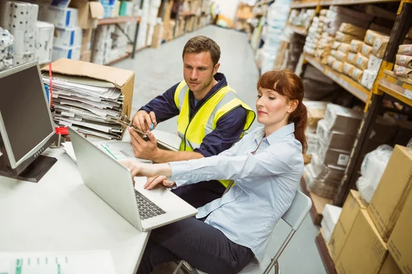 Lagerarbeiter und Manager schauen auf Laptop — Stockfoto