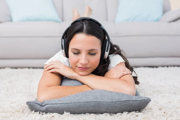 Брюнетка лежачи на килим, прослуховування музики — стокове фото