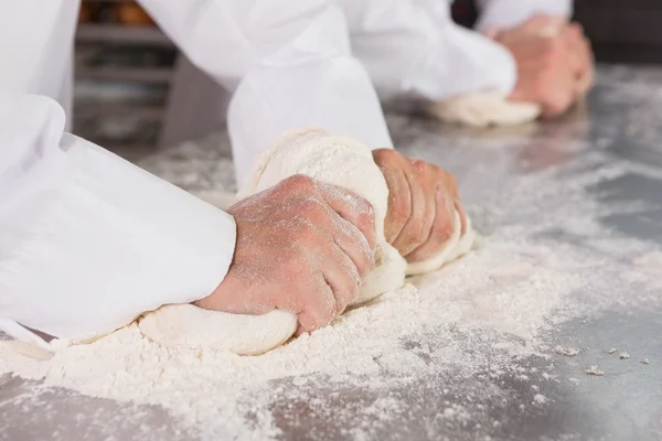 Bakkers kneden van deeg aan balie — Stockfoto