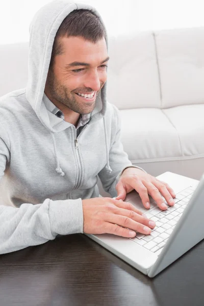 Sorrindo homem usando laptop em uma mesa — Fotografia de Stock