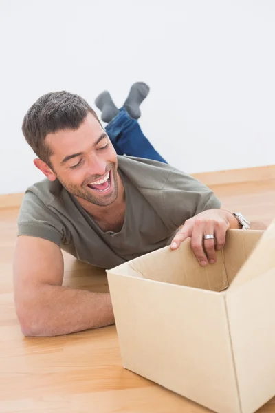 Smiling man open a moving box at home — Stock Photo, Image