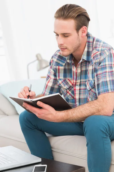 Focused man on a laptop with a notebook — Stock Photo, Image
