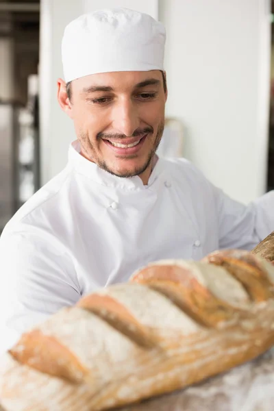 Happy baker taking out fresh loaf — Stock Photo, Image