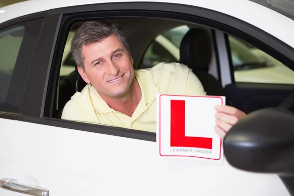 Homme tenant un panneau conducteur de l'apprenant assis derrière le volant — Photo