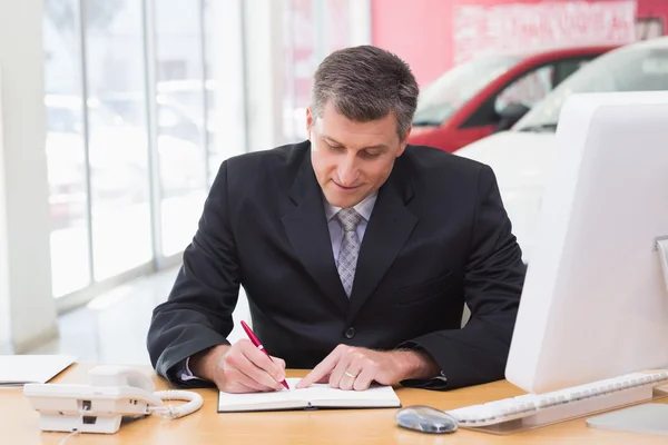 Geschäftsmann schreibt auf Klemmbrett an seinem Schreibtisch — Stockfoto