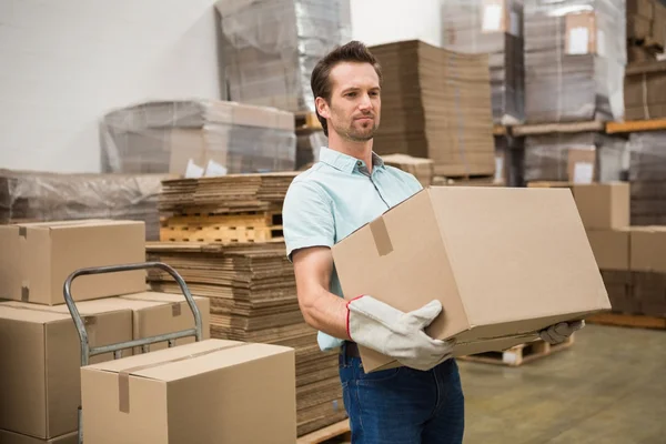 Worker carrying box in warehouse — Stock Photo, Image