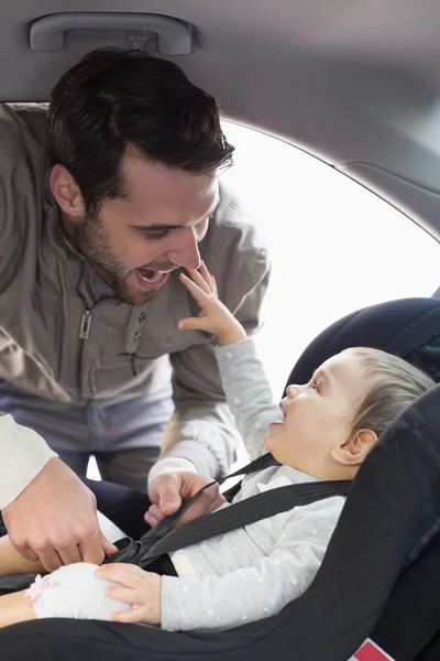 Far sikrer baby i bilsetet – stockfoto