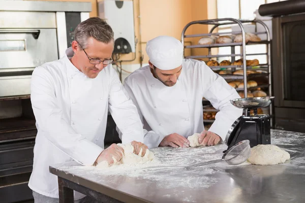 Bakers kneading dough at counter — Stock Photo, Image